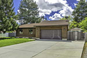 View of front of house featuring a gate, brick siding, roof with shingles, driveway, and an attached garage
