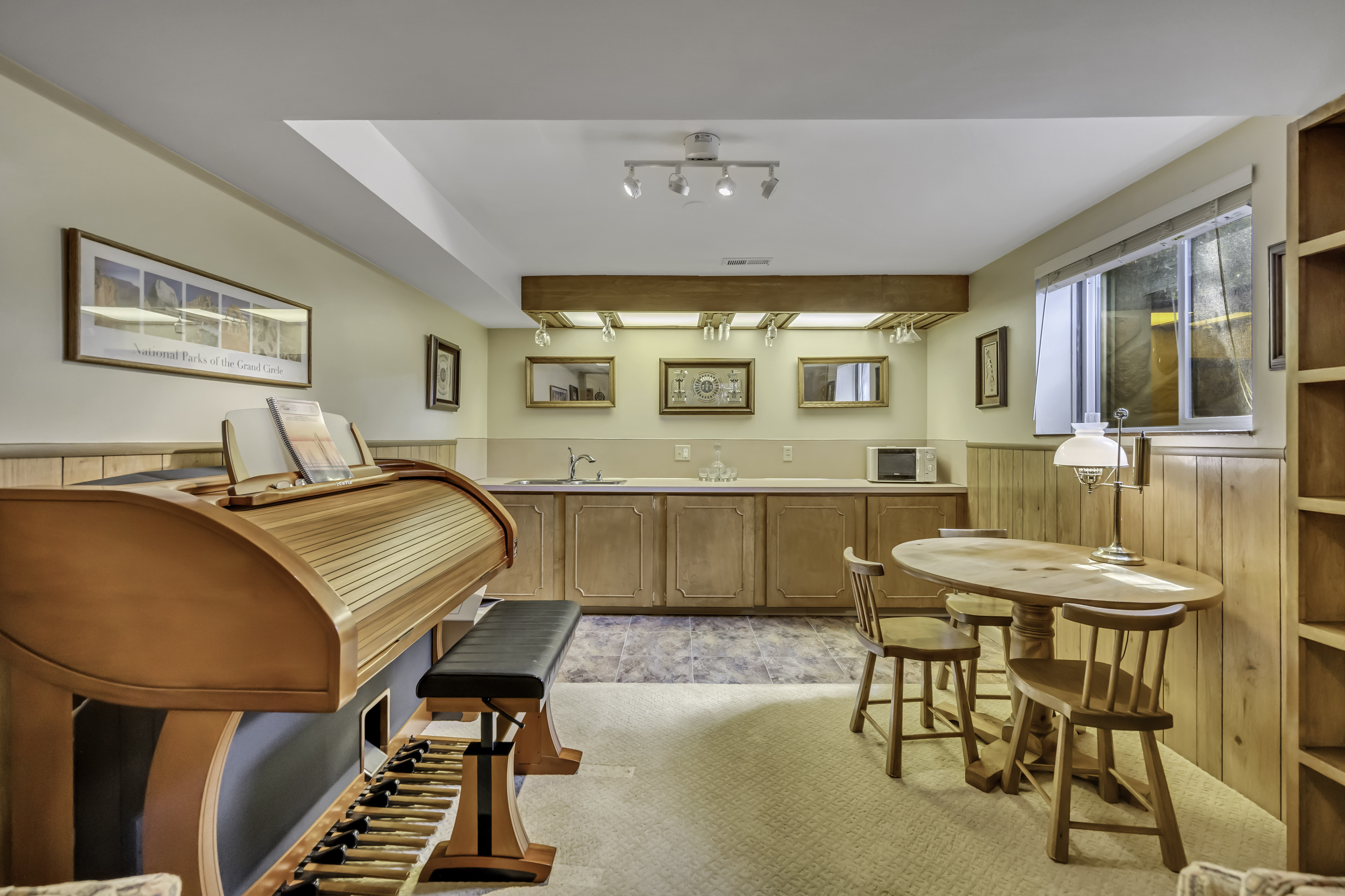 Kitchen with wainscoting, wooden walls, light countertops, light colored carpet, and open shelves