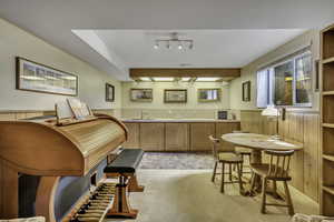 Kitchen with wainscoting, wooden walls, light countertops, light colored carpet, and open shelves