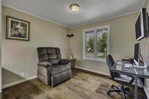 Home office with wood-type flooring and crown molding