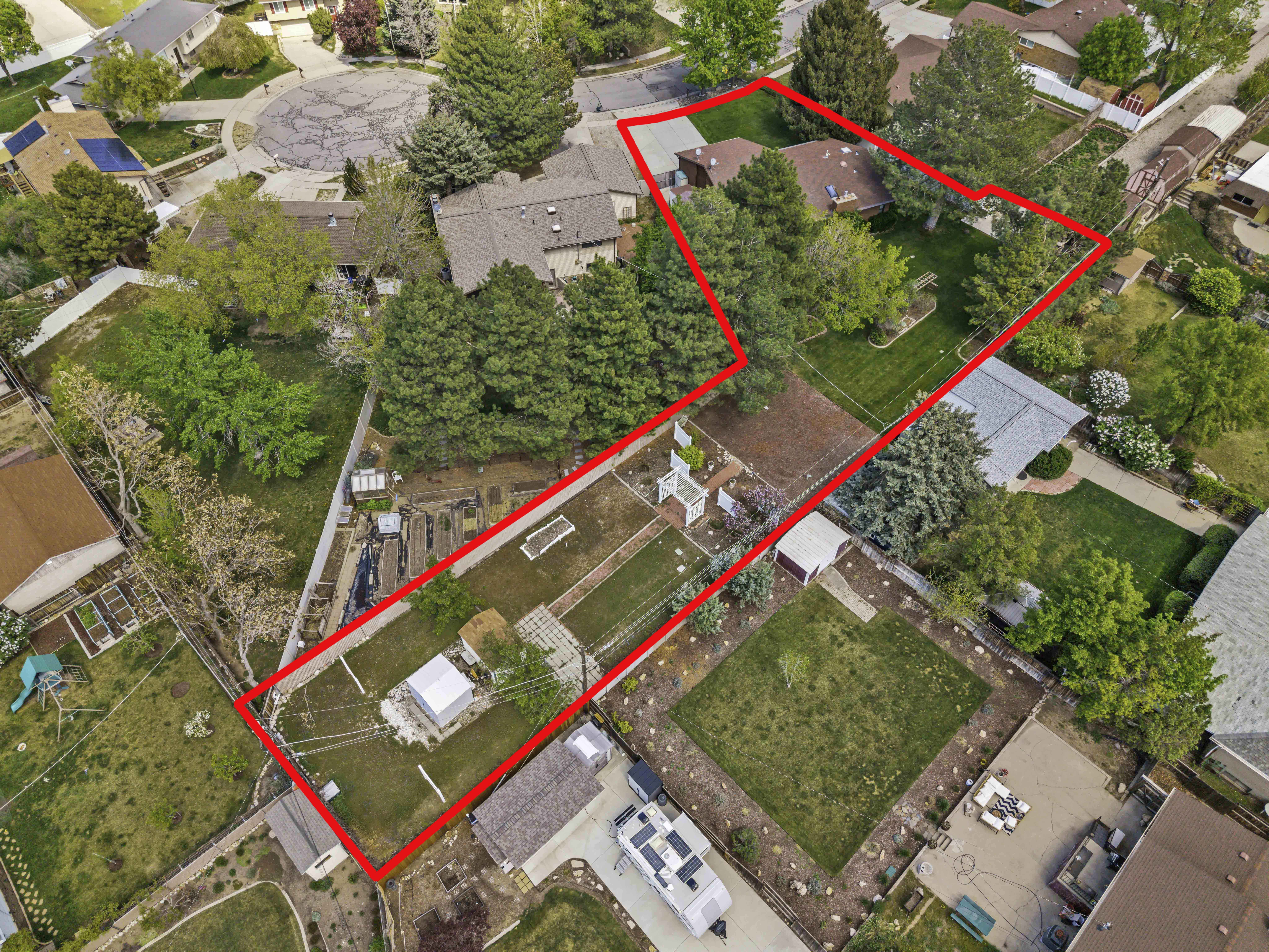 Expansive property featuring a large landscaped yard with mature trees, a detached storage shed, a paved patio area, and substantial green space