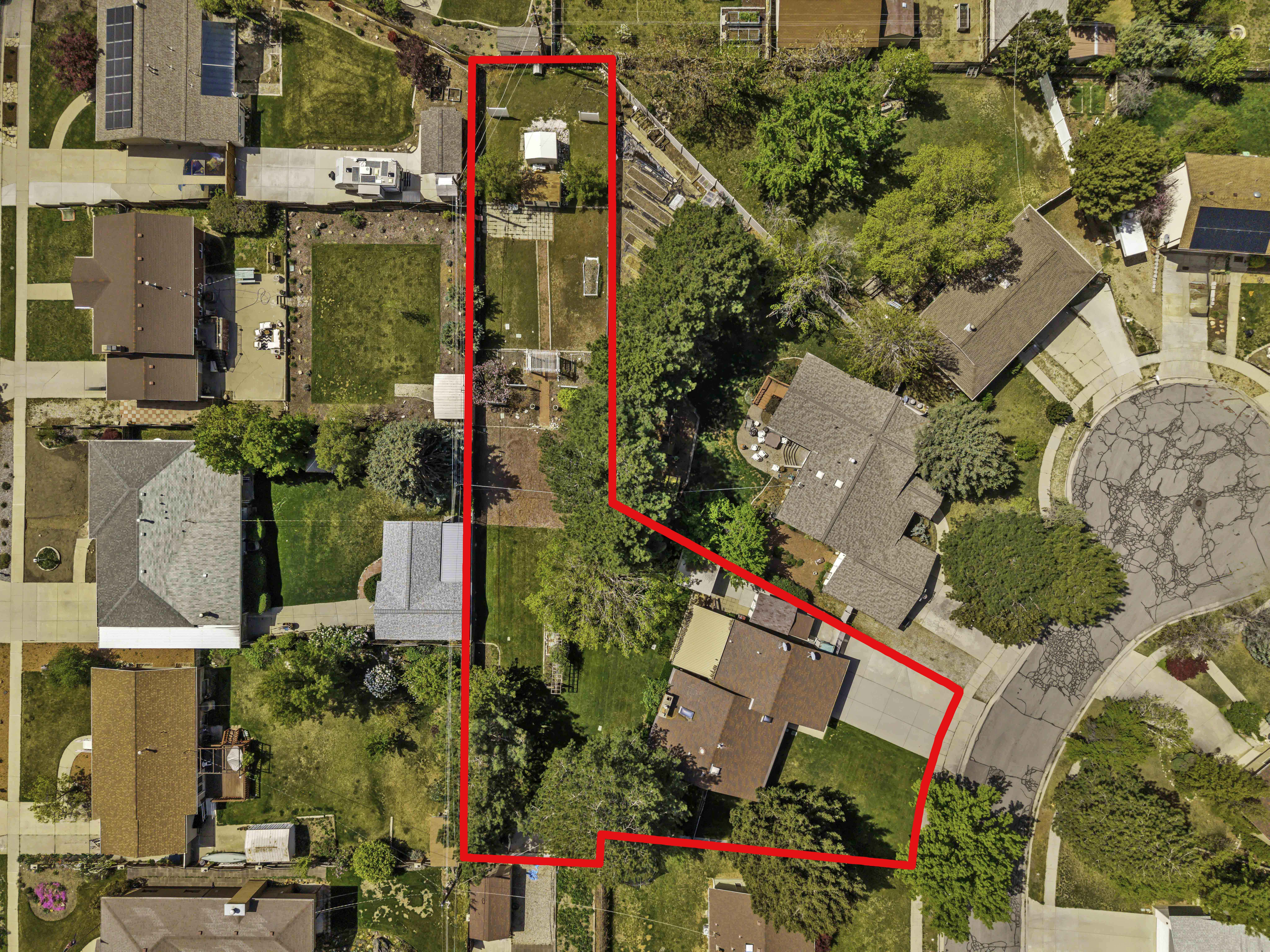 Aerial view of an expansive property featuring multiple structures, mature trees, and a long, rectangular lot