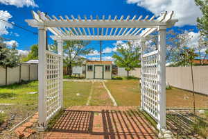 Fenced backyard featuring a storage unit, a pergola, and a patio