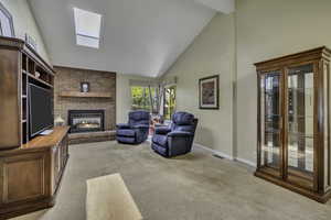 Living area featuring light colored carpet, lofted ceiling, and a fireplace