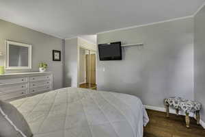 Bedroom with a closet, wood finished floors, and crown molding
