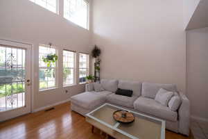 Living area with a high ceiling and lots of natural light and hardwood / wood-style floors