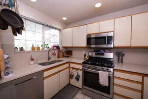Kitchen with stainless steel appliances, light tile patterned floors, recessed lighting