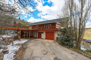 View of front of property featuring asphalt driveway, an attached garage, stucco siding, and a deck