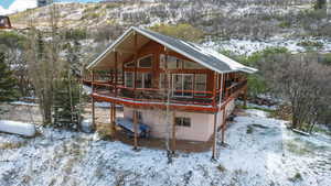 Snow covered house with a wooden deck and a patio area