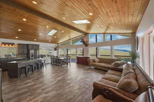 Living area featuring a high wooden beamed ceiling, a skylight, a mountain view, dark wood-type flooring, and recessed lighting