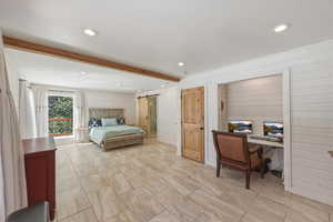 Bedroom featuring a barn door, wooden walls, recessed lighting, beamed ceiling, and an office area