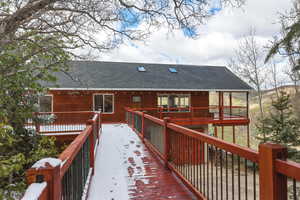 Snow covered back of property with a shingled roof