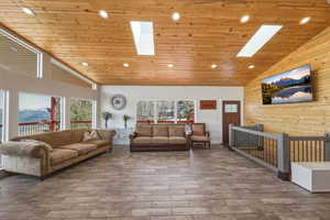 Living room with wooden walls, a vaulted wood ceiling, a skylight, recessed lighting, and a mountain view