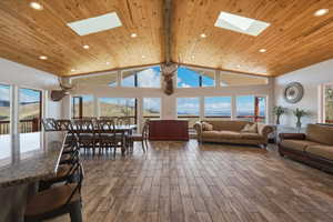 Living room with a skylight, wood tiled floors, recessed lighting, and a high wooden beamed ceiling