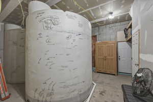 Interior space with concrete flooring, water heater, and concrete block wall