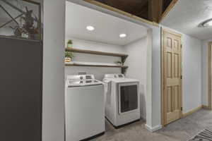 Laundry area with separate washer and dryer and light colored carpet