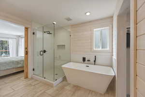 Bathroom featuring ensuite bath, a shower stall, a freestanding tub, and wood walls