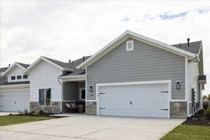 View of front of property featuring stone siding, driveway, a garage, and a shingled roof