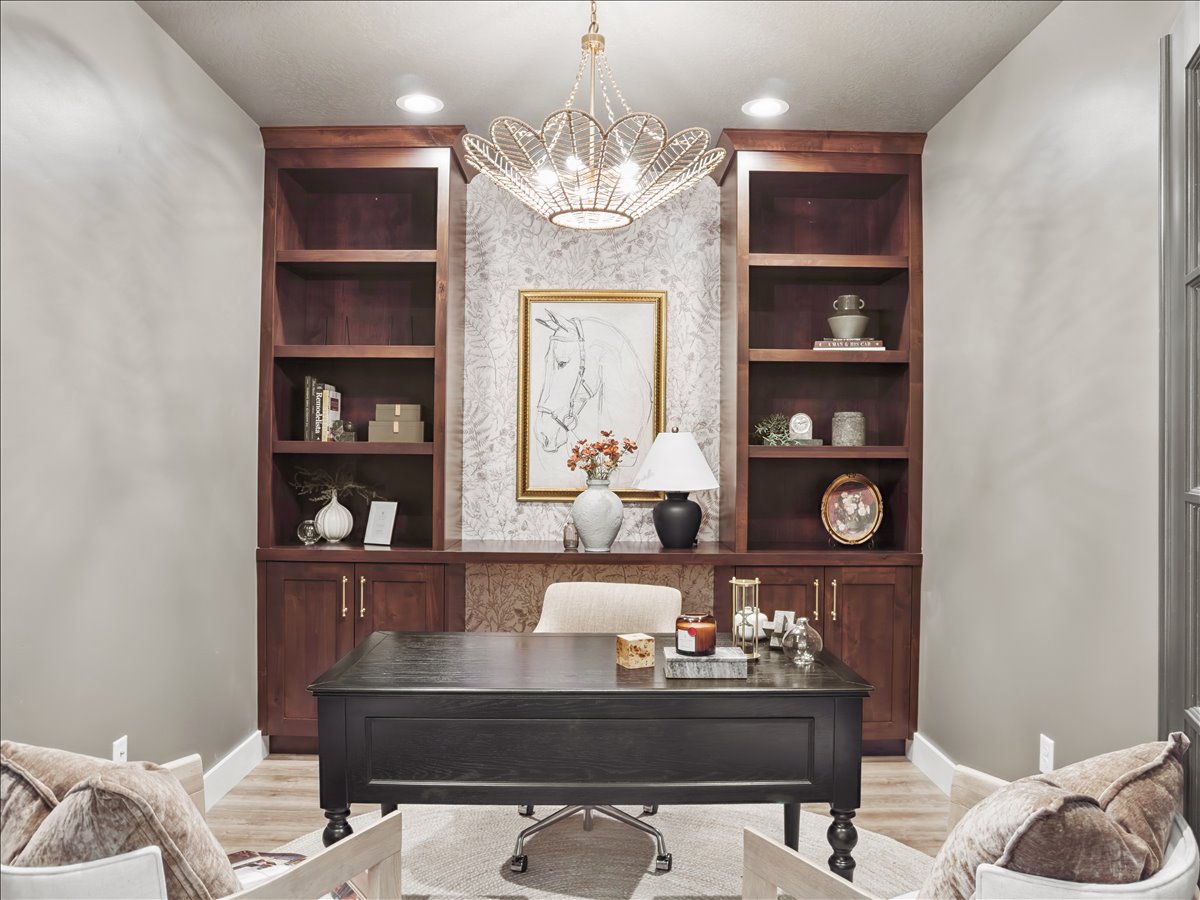 Home office featuring built in shelves, suspended lighting, and light wood-type flooring