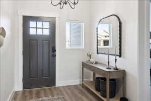 Foyer entrance with plenty of natural light, wood finished floors, and a chandelier