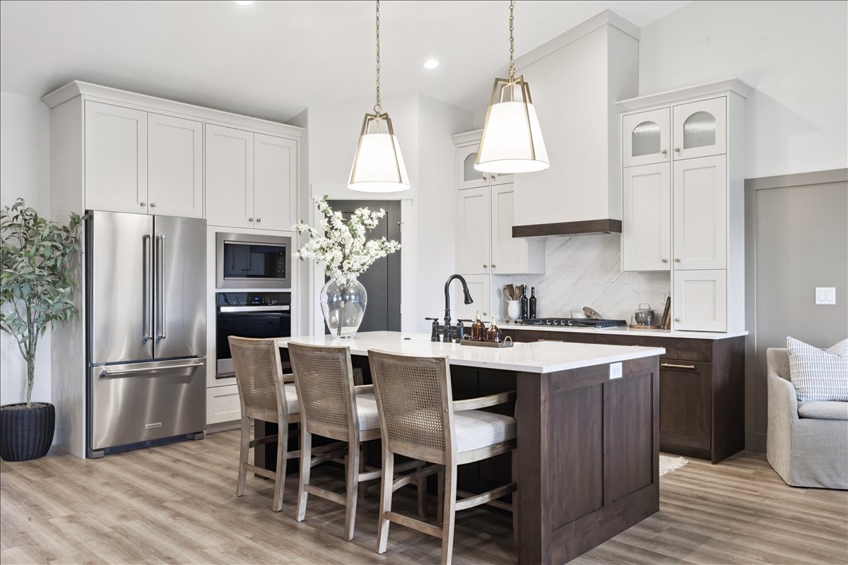 Kitchen featuring a breakfast bar area, stainless steel appliances, an island with sink, light wood-type flooring, and glass insert cabinets