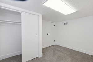 Unfurnished bedroom with a textured ceiling, light colored carpet, and a closet