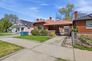 Bungalow-style house featuring a carport, concrete driveway, brick siding, and a gate