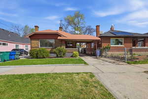 Bungalow with a chimney, driveway, brick siding, a front yard, and an attached carport