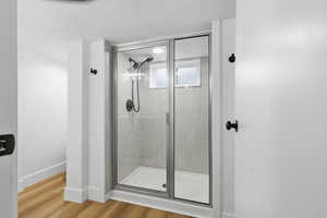 Full bathroom featuring a shower stall, light wood-type flooring, and a textured ceiling