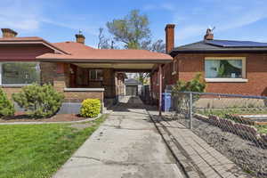 View of front of home with a gate, a chimney, and brick siding