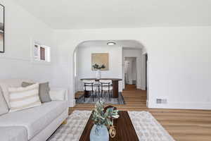 Living room with light wood-style flooring, arched walkways, and a textured ceiling