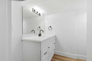 Bathroom with vanity, light wood-style floors, and a textured ceiling