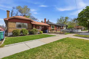 View of front of home featuring roof mounted solar panels, a chimney, brick siding, and a gate