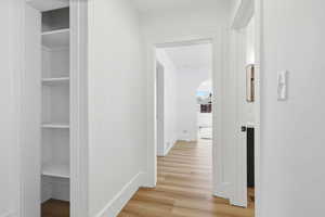 Corridor with light wood-style floors and baseboards