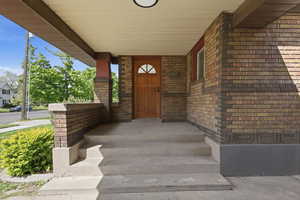 Entrance to property with brick siding and covered porch