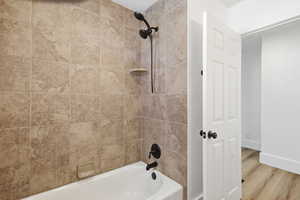 Full bath featuring shower / washtub combination and wood finished floors