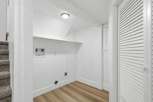 Laundry area with light wood-style flooring, hookup for a washing machine, and hookup for an electric dryer