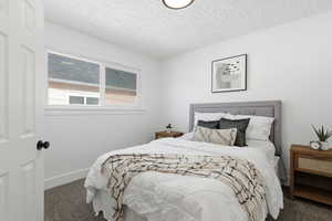 Bedroom with dark carpet and a textured ceiling