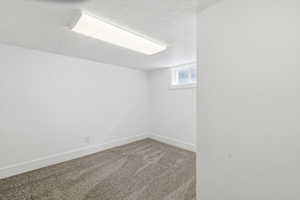 Carpeted empty room with baseboards and a textured ceiling