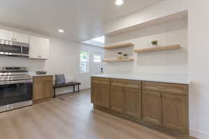 Dual tone kitchen featuring stainless steel appliances, recessed lighting, two tone color scheme, light wood-style flooring, and open shelves