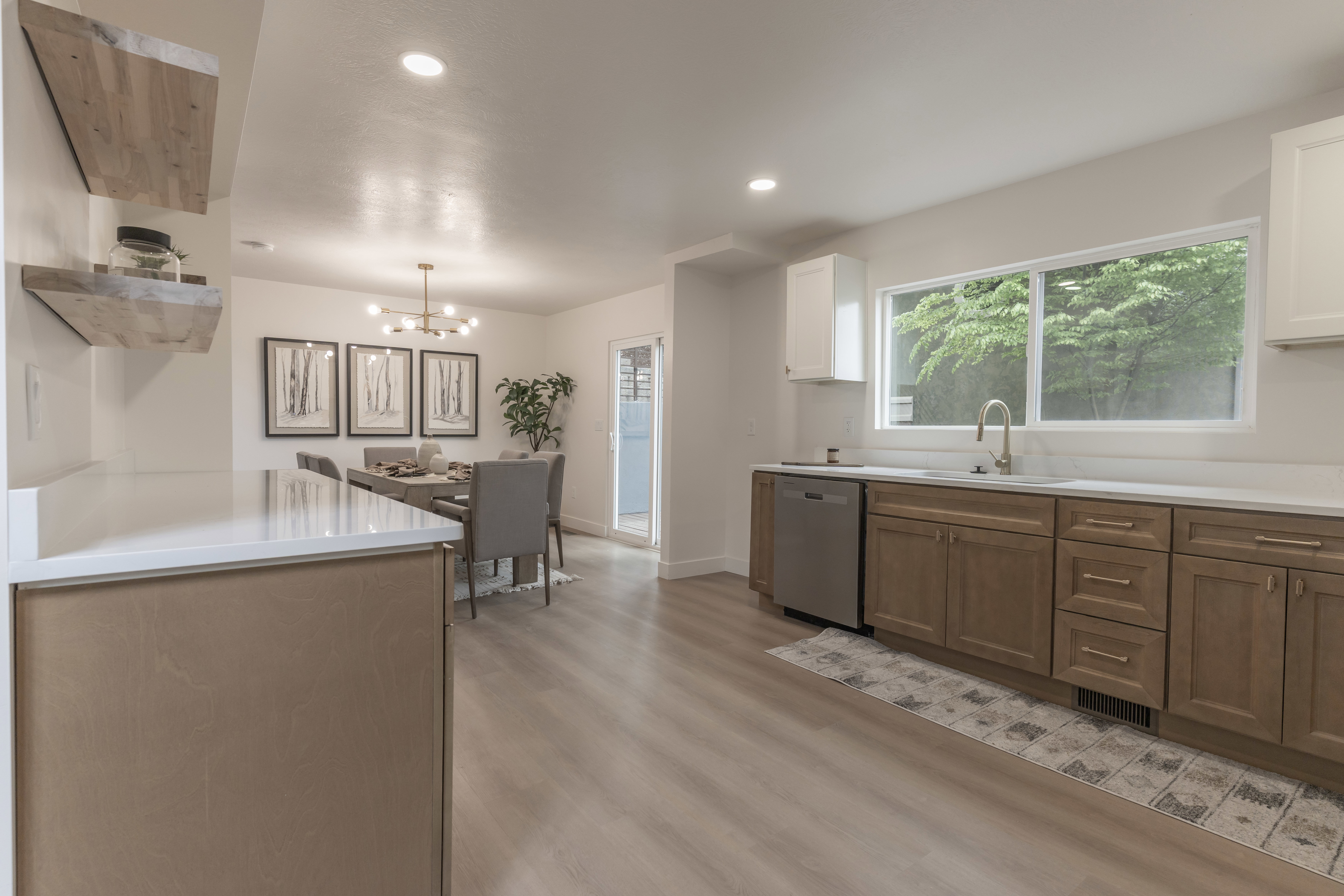 Kitchen with dual tone cabinets, suspended lighting, stainless steel dishwasher, open shelves, and light wood-style floors