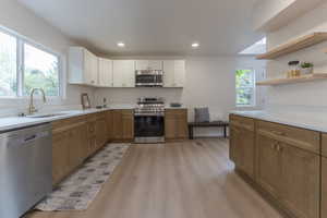 Dual tone kitchen featuring stainless steel appliances, open shelves, light wood-type flooring, two tone cabinetry, and recessed lighting