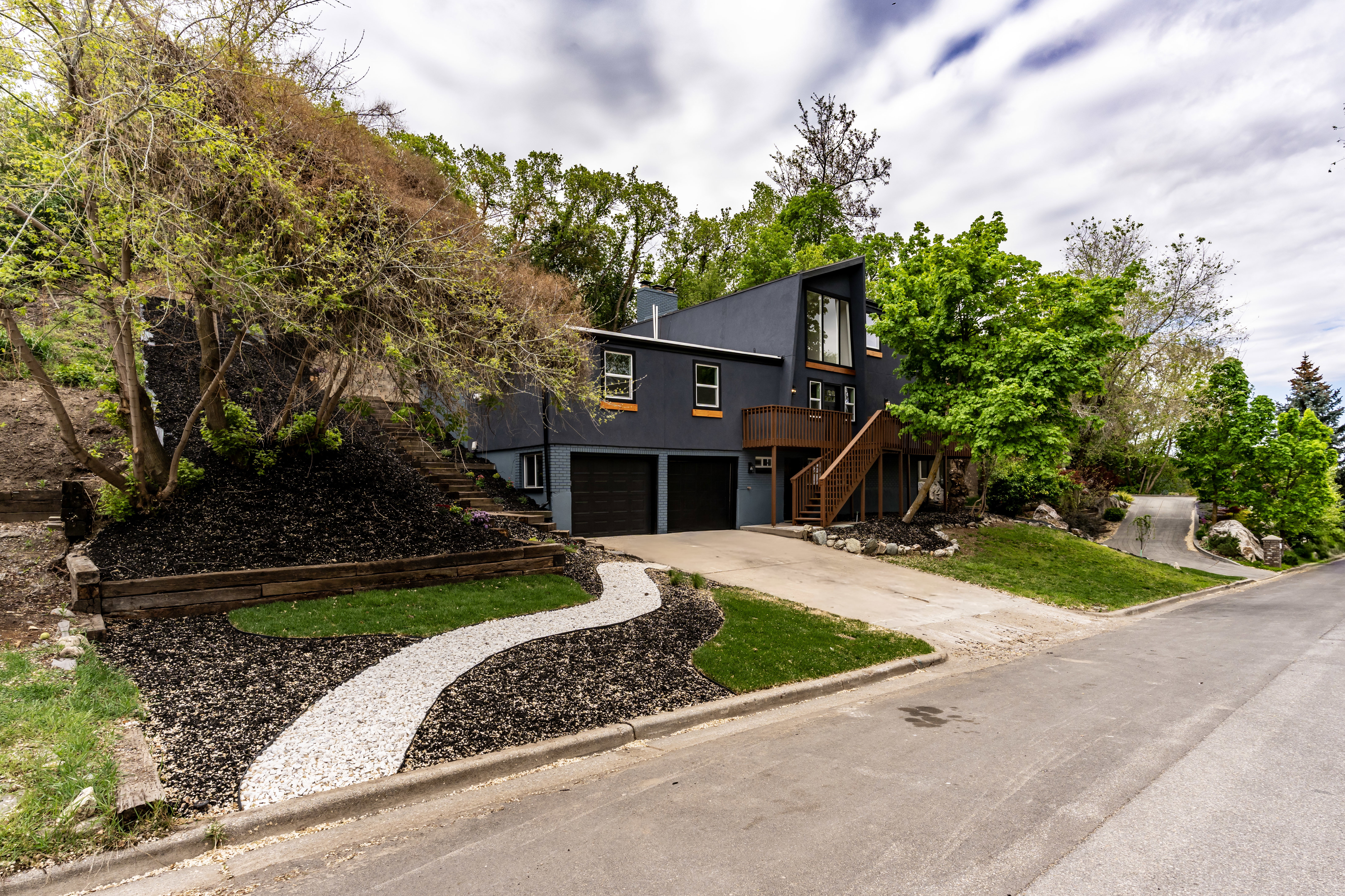 View of front facade with concrete driveway, stucco siding, a deck, a chimney, and an attached garage