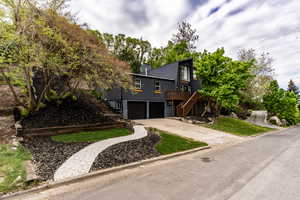 View of front facade with concrete driveway, stucco siding, a deck, a chimney, and an attached garage