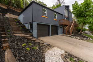 View of front of house with brick siding, stucco siding, concrete driveway, a garage, and a deck