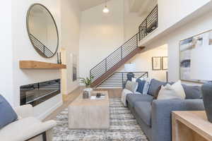 Living room featuring a high ceiling, light wood-style flooring, and a glass covered fireplace