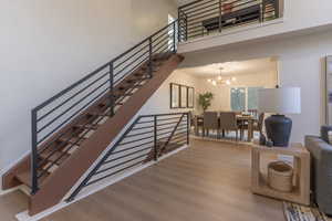 Staircase featuring wood finished floors, suspended lighting, and a high ceiling