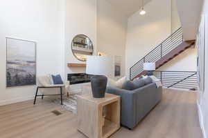 Living room with a high ceiling, light wood-style floors, and a glass covered fireplace