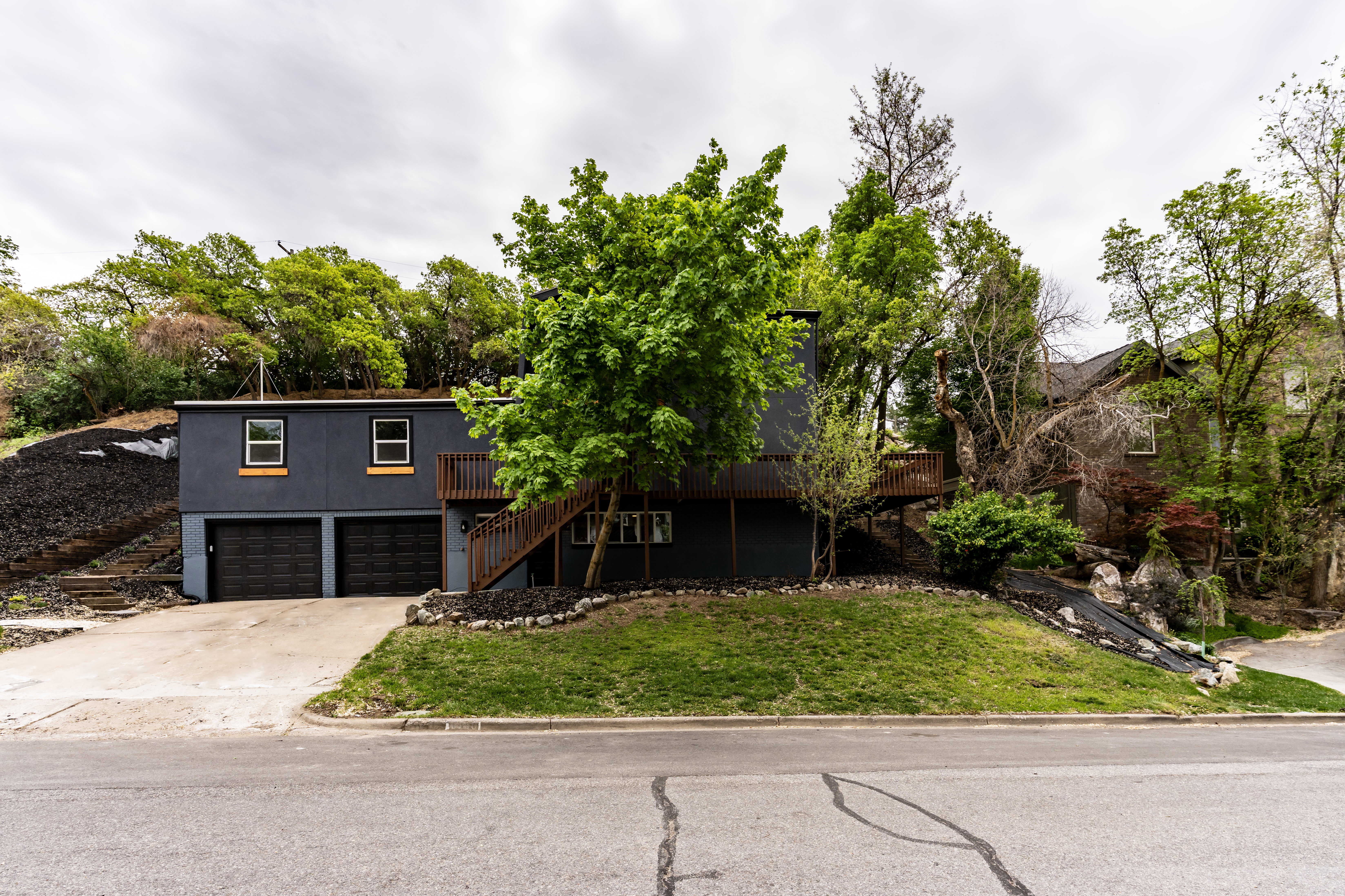View of front of property featuring a wooden deck, a front yard, driveway, and a garage