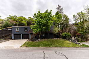 View of front of property featuring a wooden deck, a front yard, driveway, and a garage